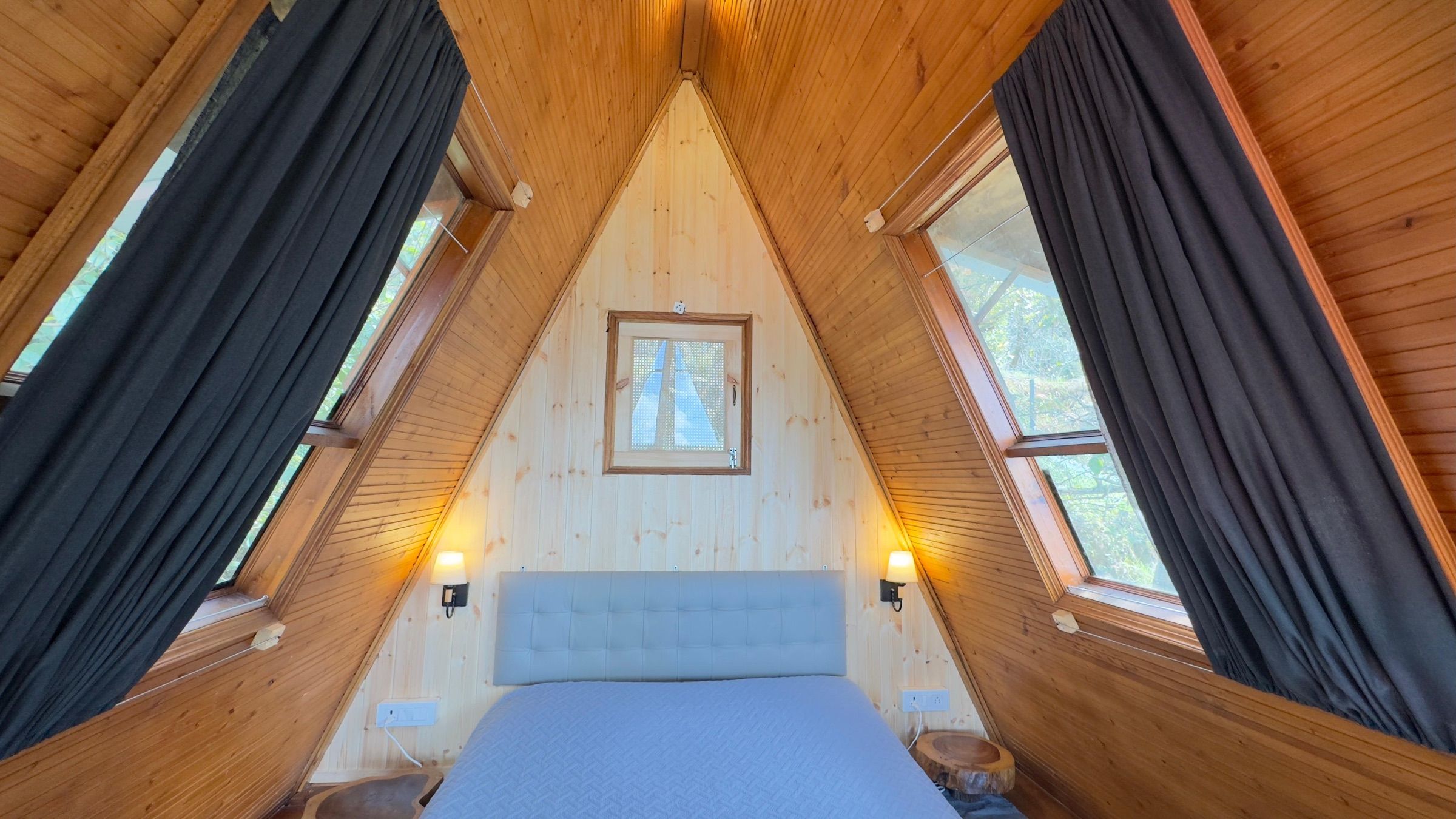 The bed in the A-frame loft, under the slope of the wooden roof