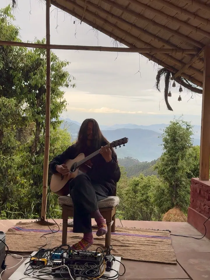 Someone playing the guitar at the edge of Turiya, with the hills behind