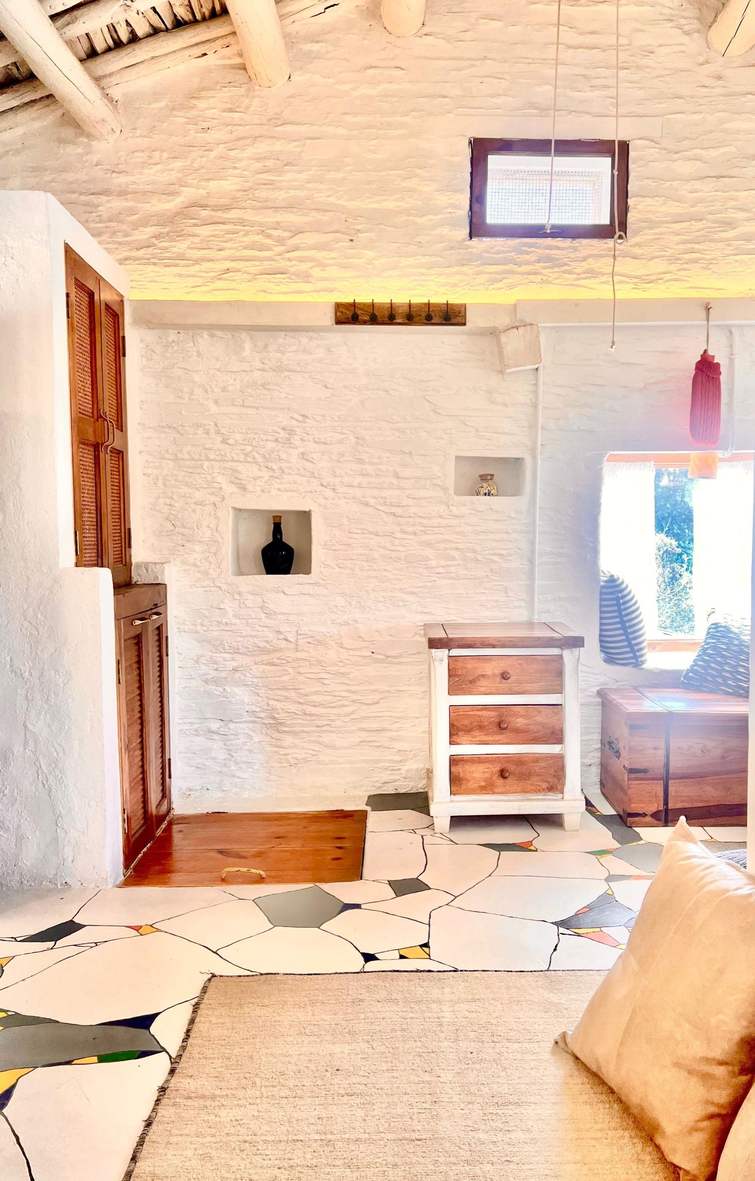 Kintsugi's high ceiling with log beams, a chest of drawers and the painted floor