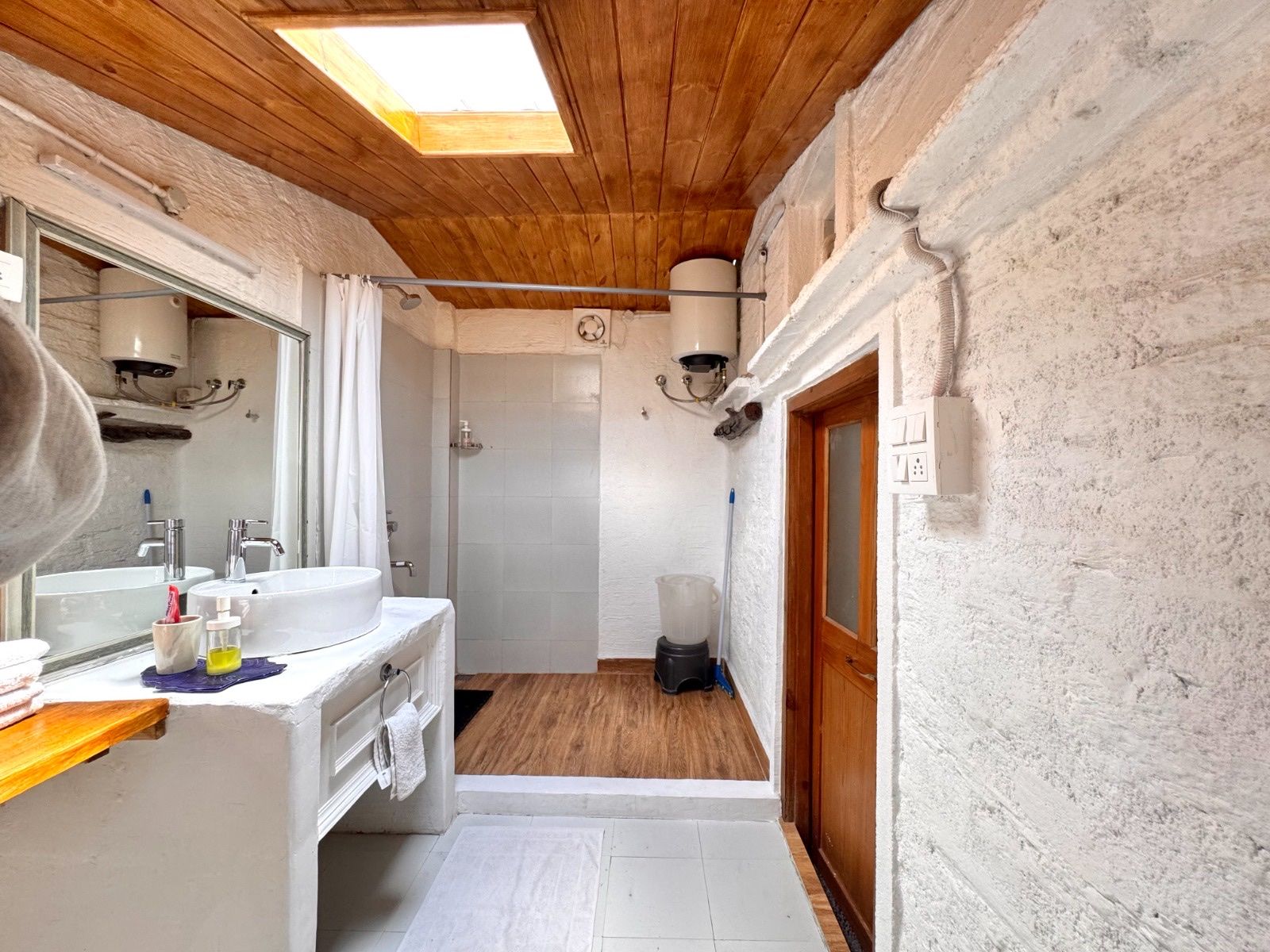 A bathroom under a wooden ceiling with a skylight